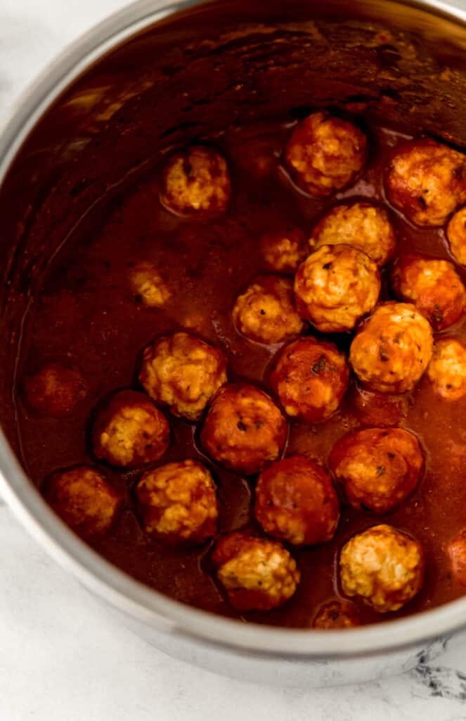 instant pot insert with frozen meatballs and sauce in it.