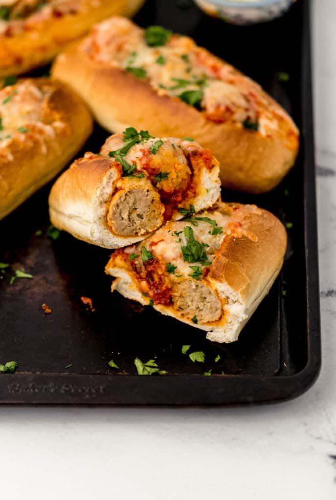 meatball sandwich cut in half on sheet pan