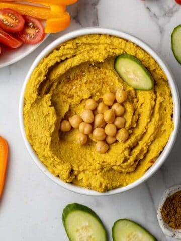 curry hummus in white bowl with vegetables