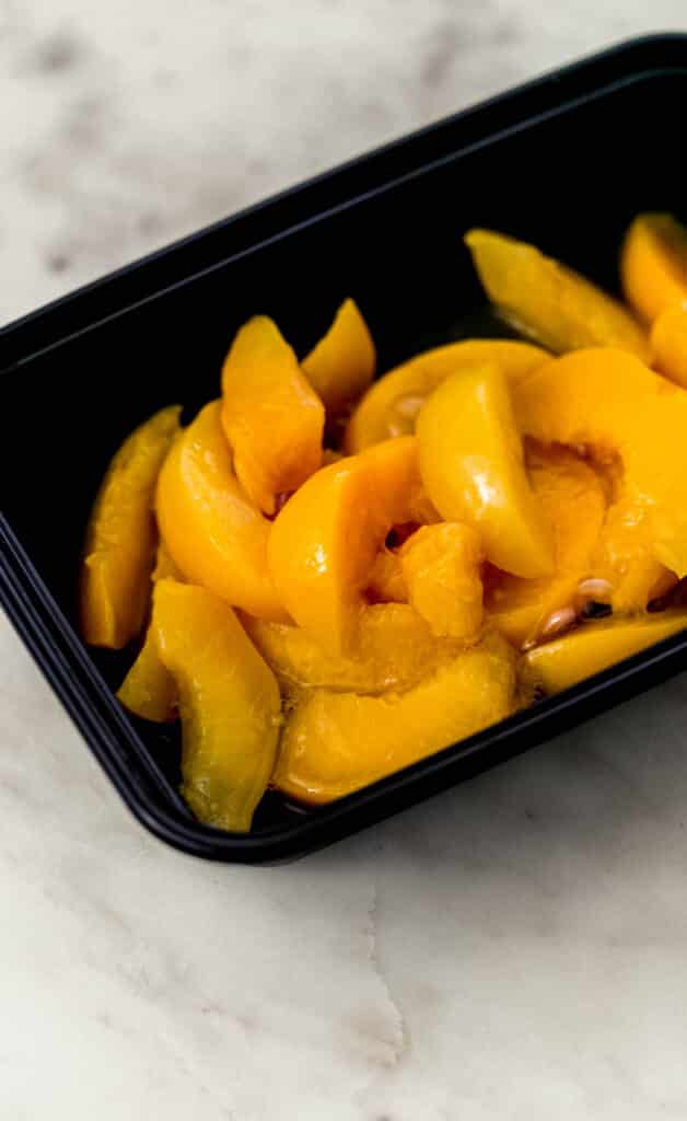 black container with sliced peaches in it