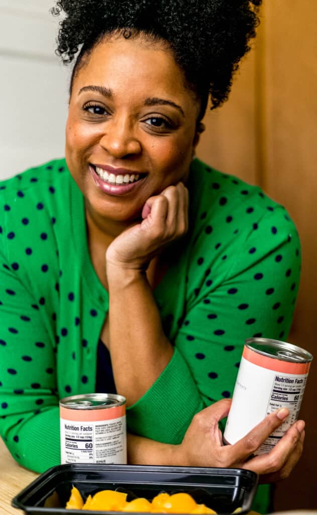 simply lakita with cans of peaches in kitchen
