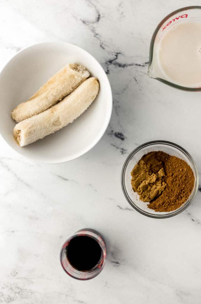 ingredients needed to make smoothie on marble surface in separate containers