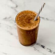Close up view of finished smoothie in glass with straw.