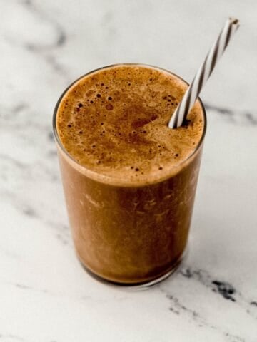 Close up view of finished smoothie in glass with straw.