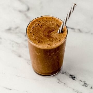 Close up view of finished smoothie in a glass with a straw.