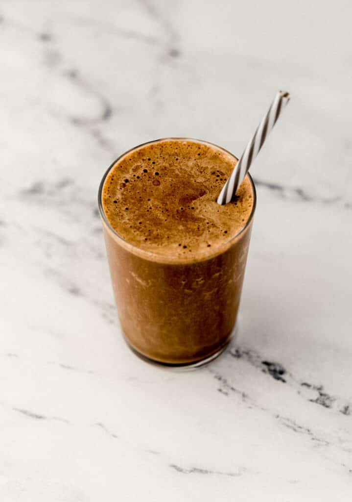 mocha smoothie in glass with straw on marble surface 