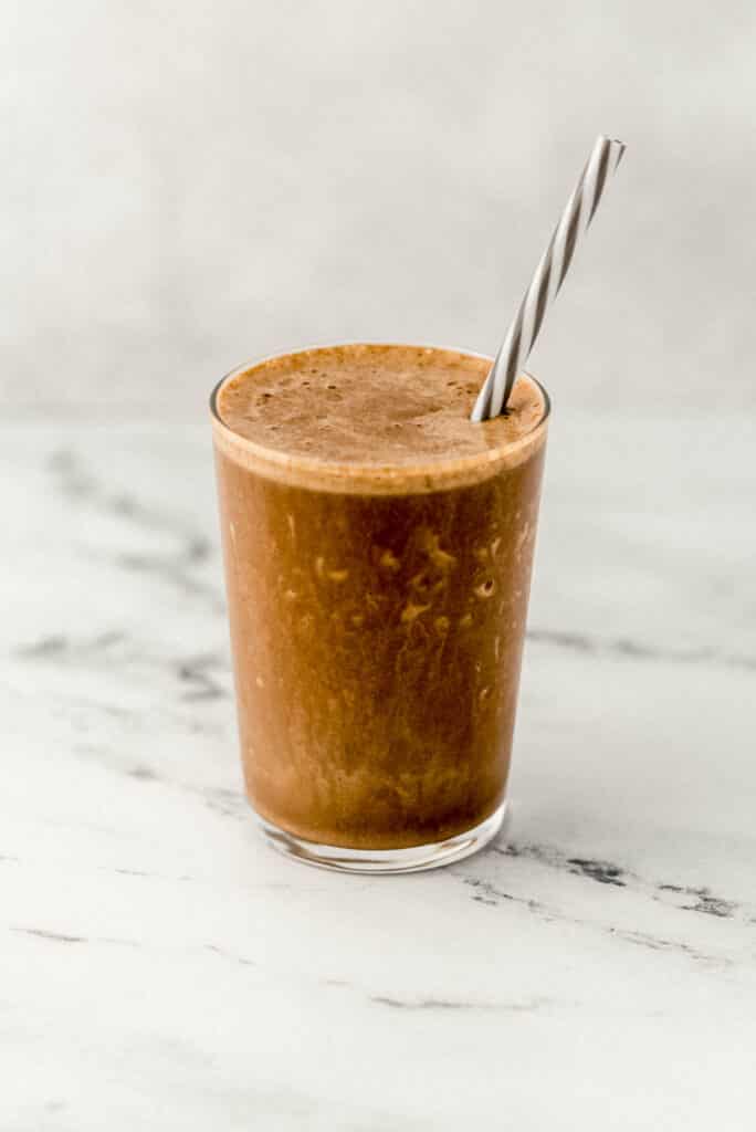 close up side view mocha smoothie in a glass with a straw