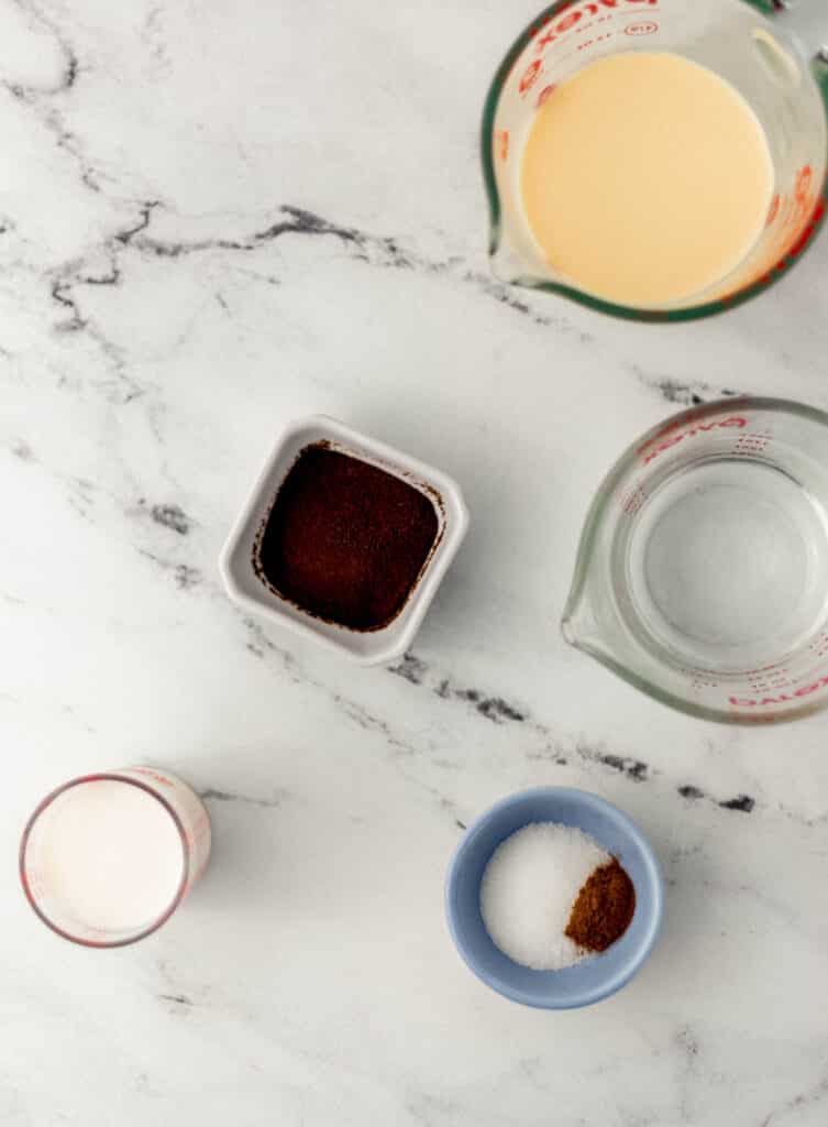 ingredients to make eggnog latte in separate containers on marble surface