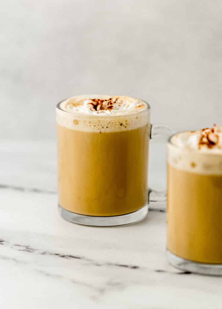 two finished lattes in glass mugs on marble surface 