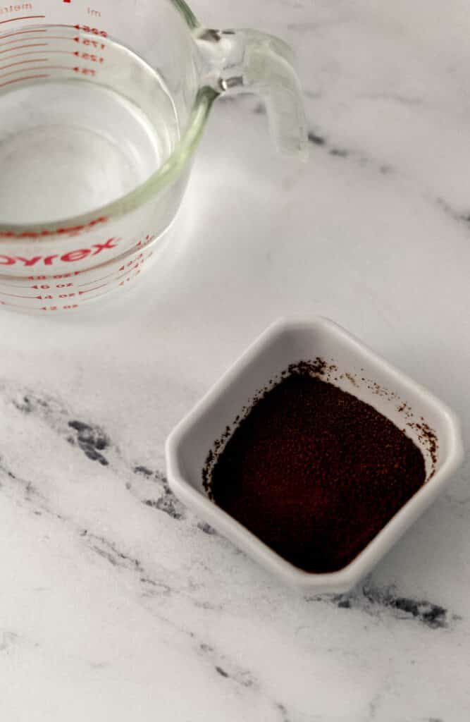 small pyrex of hot water and white square bowl of espresso powder 