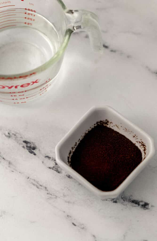 small pyrex of hot water and white square bowl of espresso powder