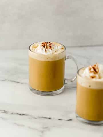 close up side view of two eggnog lattes in glass mugs