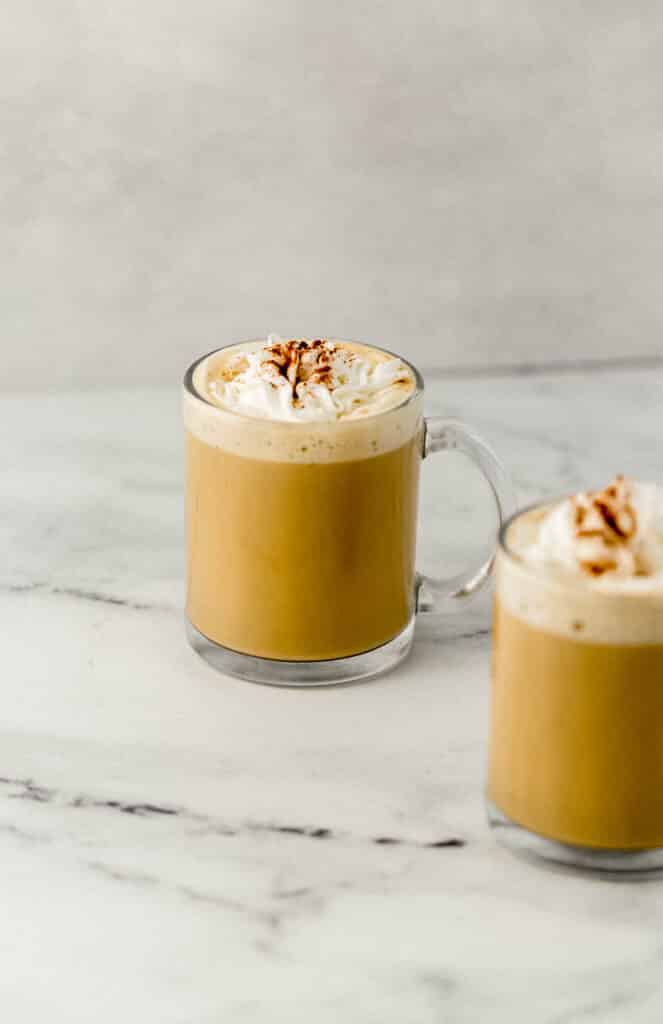 close up side view two eggnog lattes in glass mugs