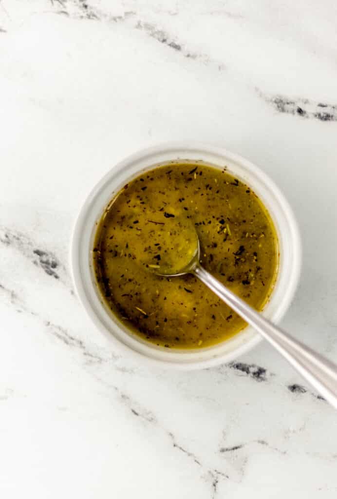 small white bowl with spoon and sauce to spread on bread