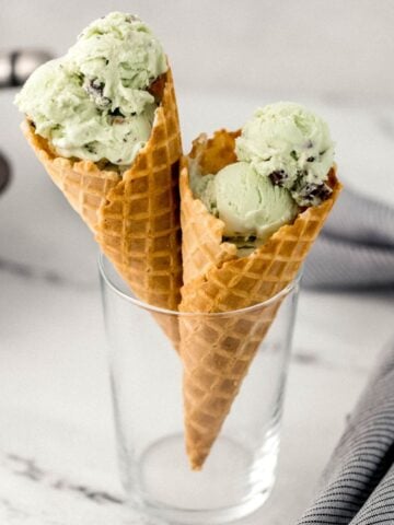 close up side view of two chocolate mint waffle cones in glass