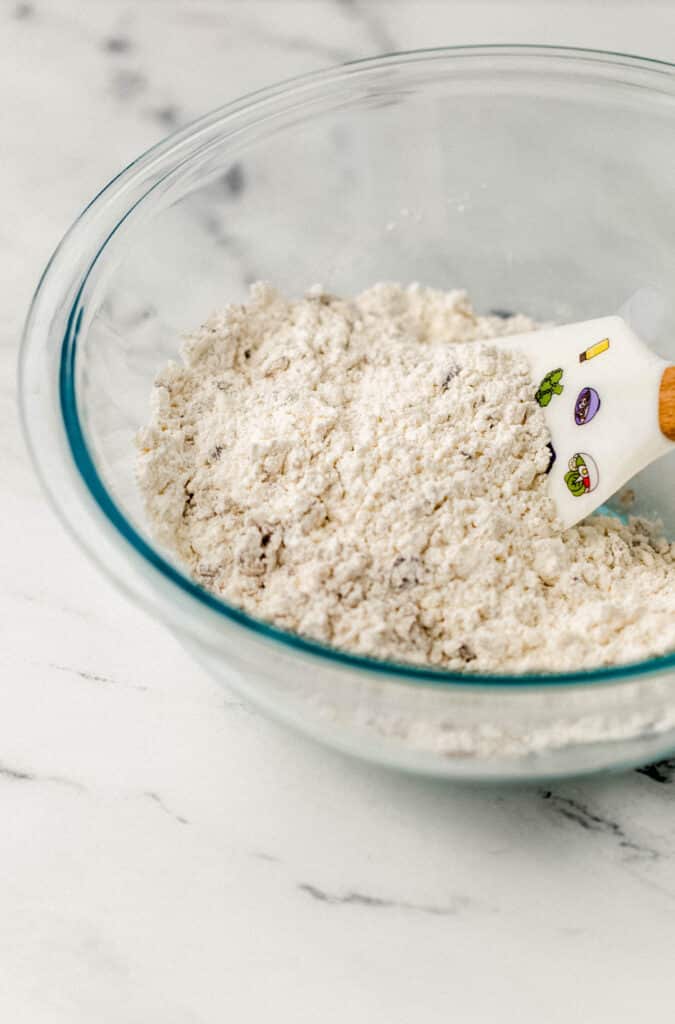 glass mixing bowl with dry ingredients and rubber spatula 