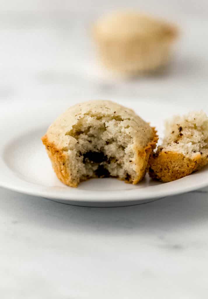 single muffin on small white plate with a bite in it. 