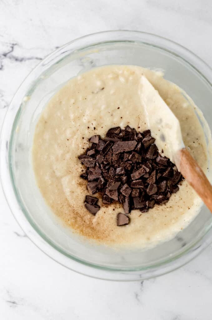 all ingredients to make muffins in glass mixing bowl with spatula 