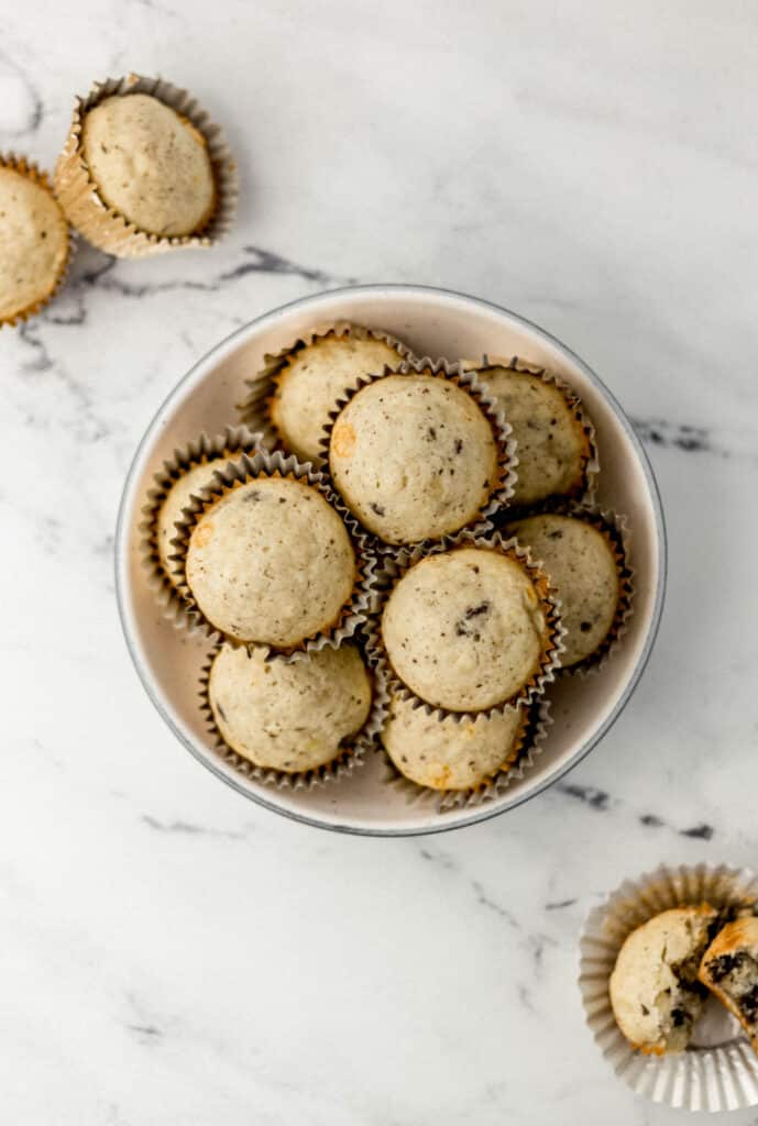 mexican chocolate banana muffins in gold liners inside a white bowl on a marble surface
