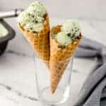 close up side view mint chocolate ice cream cones in glass beside cloth napkin