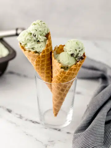 close up side view mint chocolate ice cream cones in glass beside cloth napkin