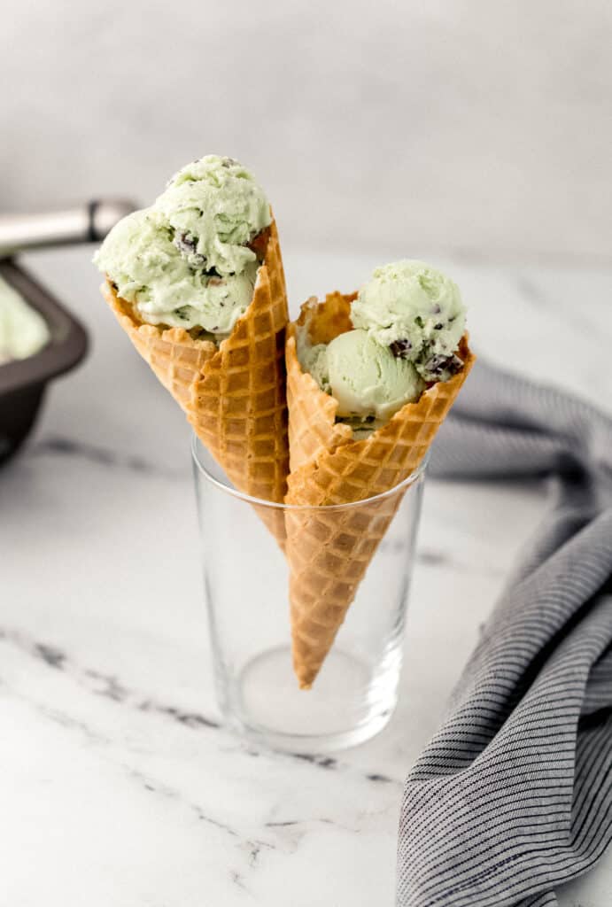 close up side view mint chocolate ice cream cones in glass beside cloth napkin