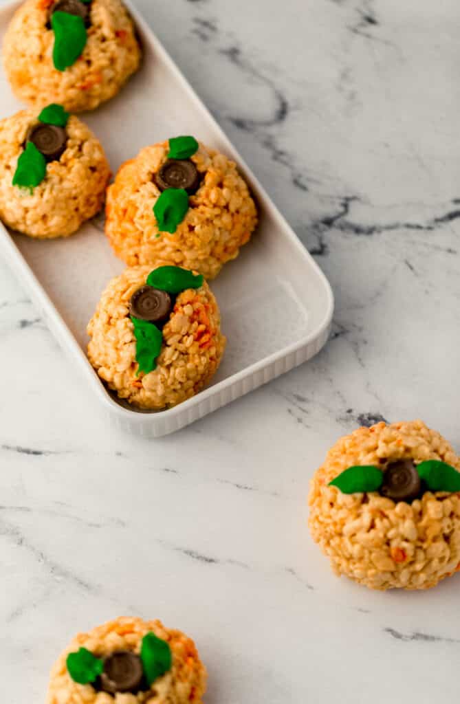 pumpkin rice krispie treats on rectangle platter and marble surface. 