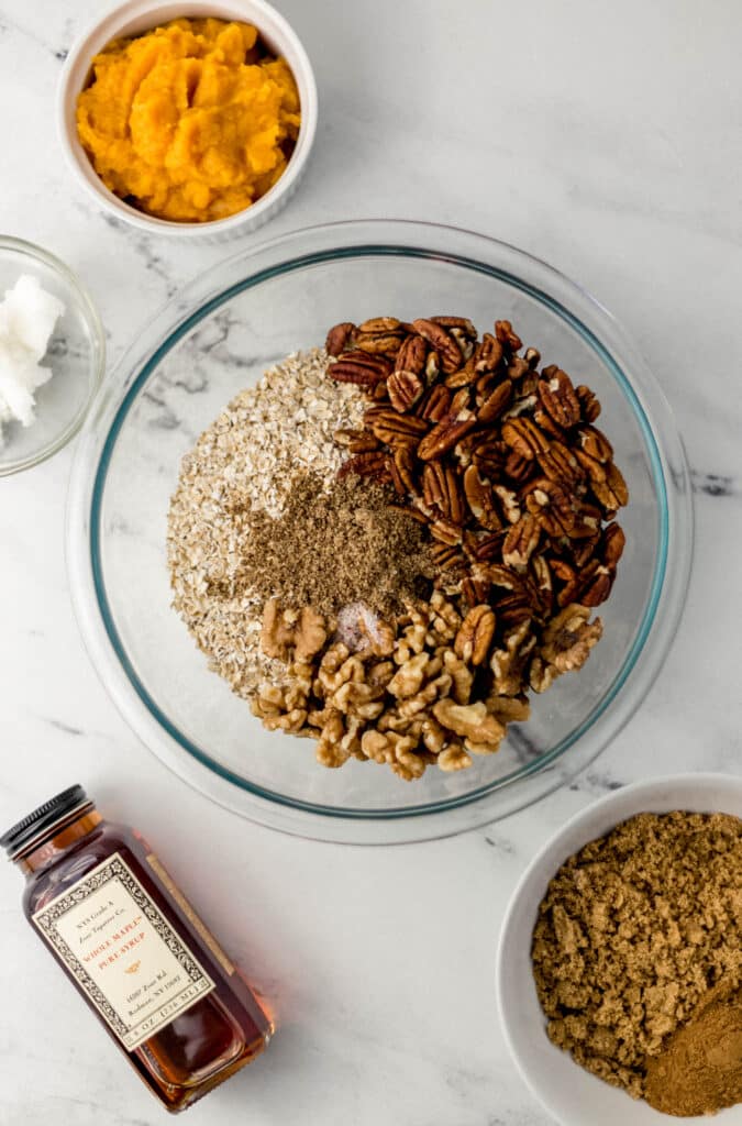 ingredients needed for pumpkin spice granola on marble surface in separate containers