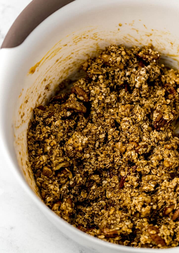 ingredients combined to make granola in white mixing bowl