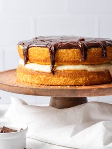 close up side view Boston cream cake on wooden cake stand with cloth napkin