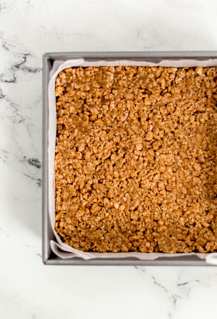 crispy rice treats pressed into square parchment lined baking pan 