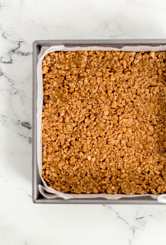 crispy rice treats pressed into square parchment lined baking pan