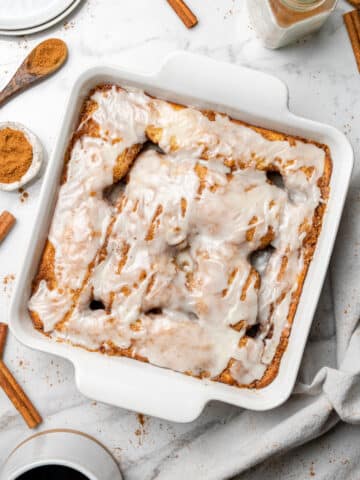 overhead view of cinnamon roll cake in a white square baking dish