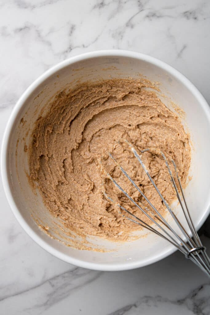 overhead view of cinnamon mixture in white mixing bowl with whisk