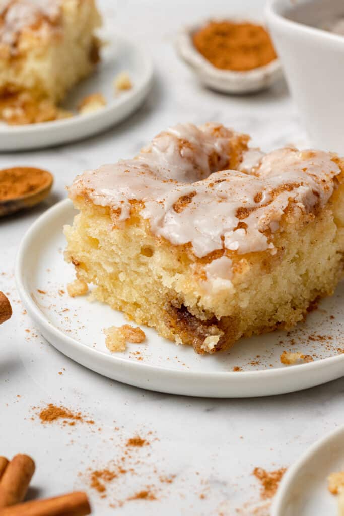 close up side view of a slice of cinnamon roll cake on a white plate 