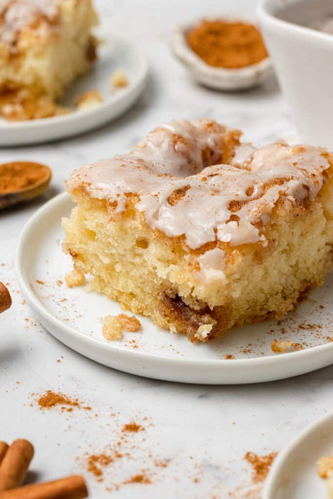 close up side view of a slice of cinnamon roll cake on a white plate