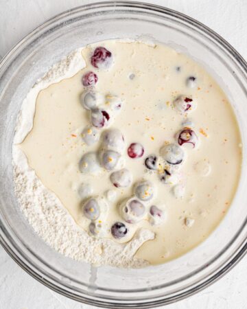 Wet and dry ingredients combined in large glass mixing bowl.