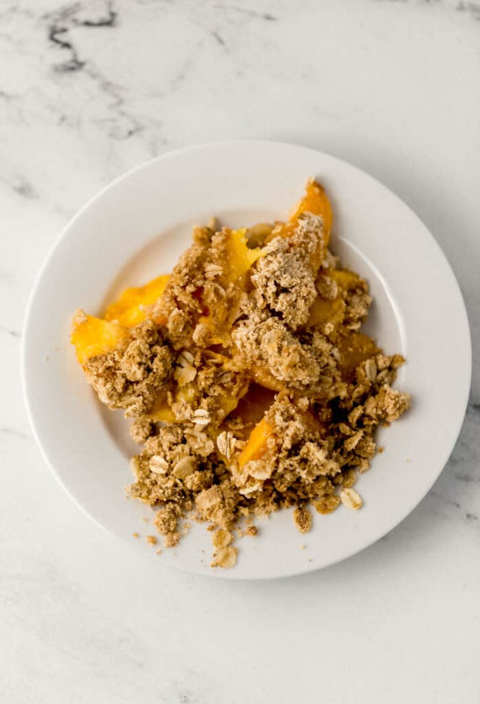 single serving of peach crisp on small white plate
