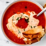 Overhead view of bowl of soup with grilled cheese in it.