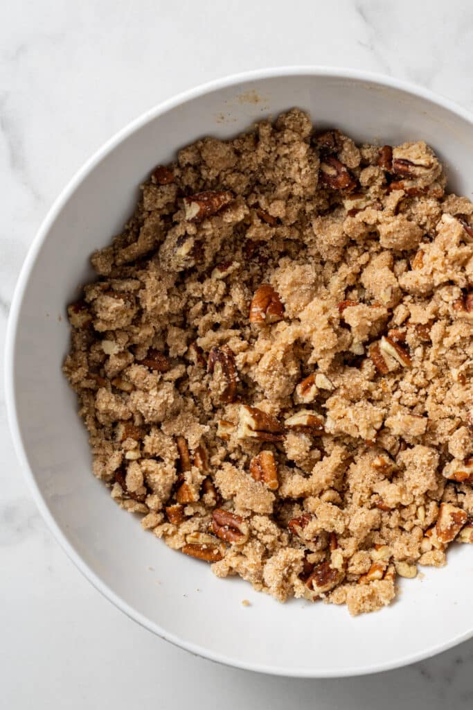 overhead view white mixing bowl with ingredients for streusel combined