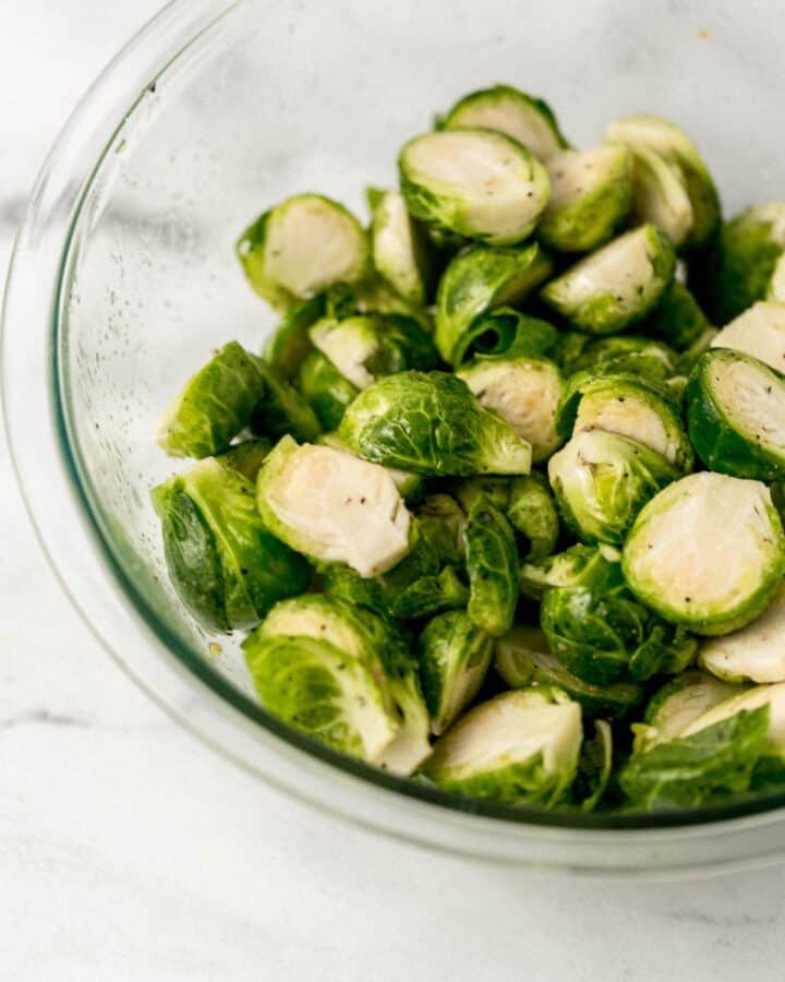 Close up front view of prepared brussel sprouts tossed in oil and spices. 