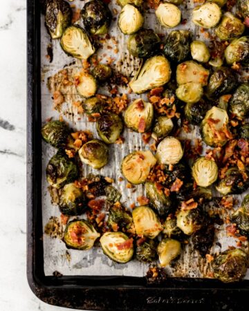 Overhead view of brussel sprouts and bacon on parchment lined baking sheet.