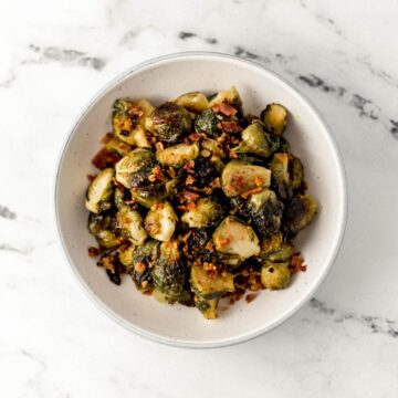 Overhead view of finished brussel sprouts in white bowl with bacon.