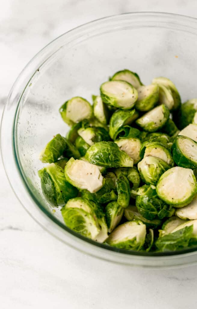close up view of seasoned brussels sprouts in large glass bowl 