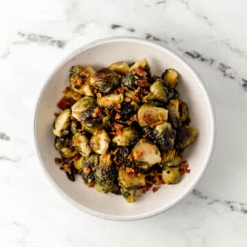 overhead view of maple roasted brussels sprouts in large white bowl on marble surface