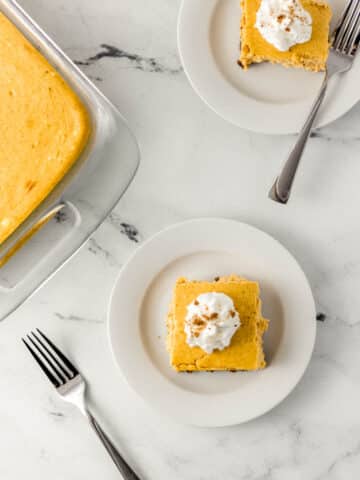 overhead view pumpkin cheesecake on two white plates with forks and in a glass baking dish