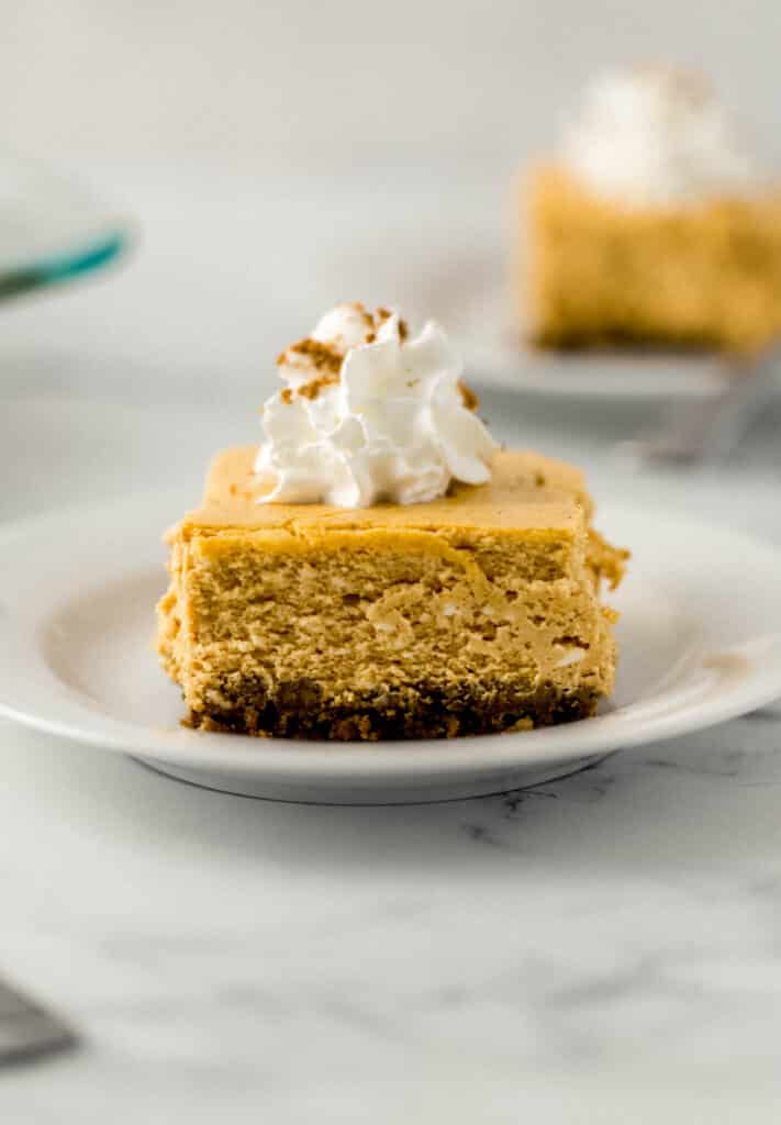 close up side view pumpkin cheesecake slice on white plate