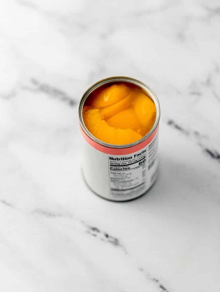 open can on cling peaches on marble surface 