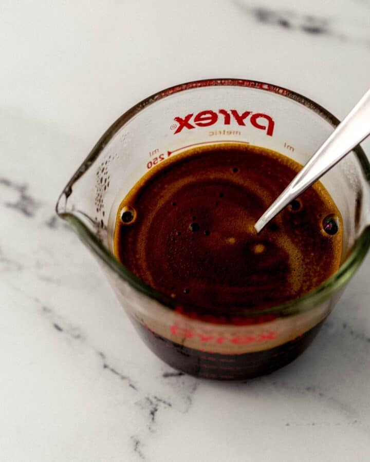 Glass measuring cup with espresso and spoon in it.