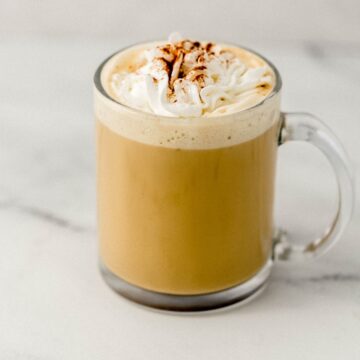 Close up side view of finished eggnog latte in glass mug.